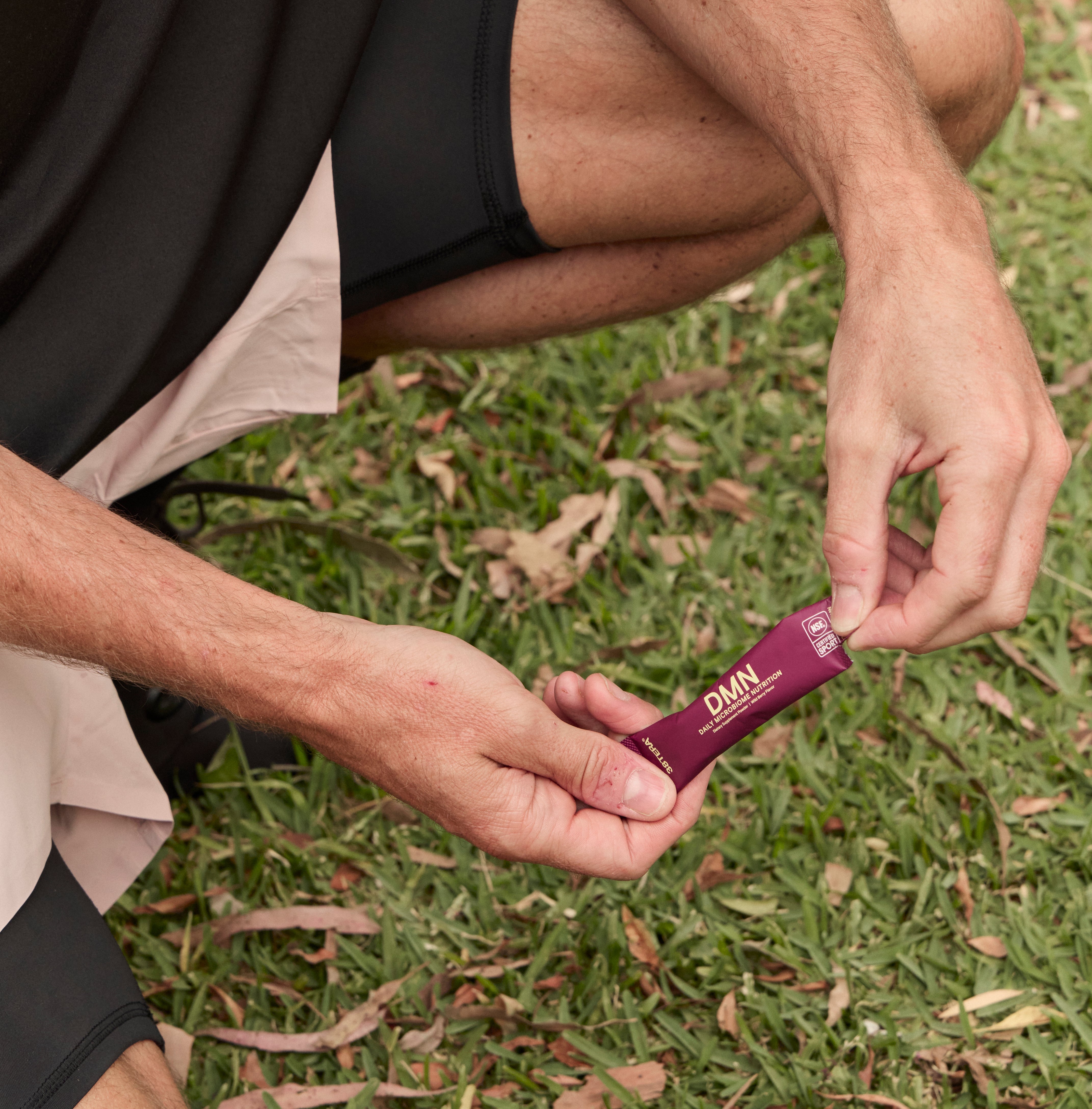 Person holding a DMN sachet purple on grass